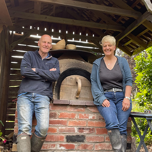 Kate and Martin Priddy standing in front of their bread oven